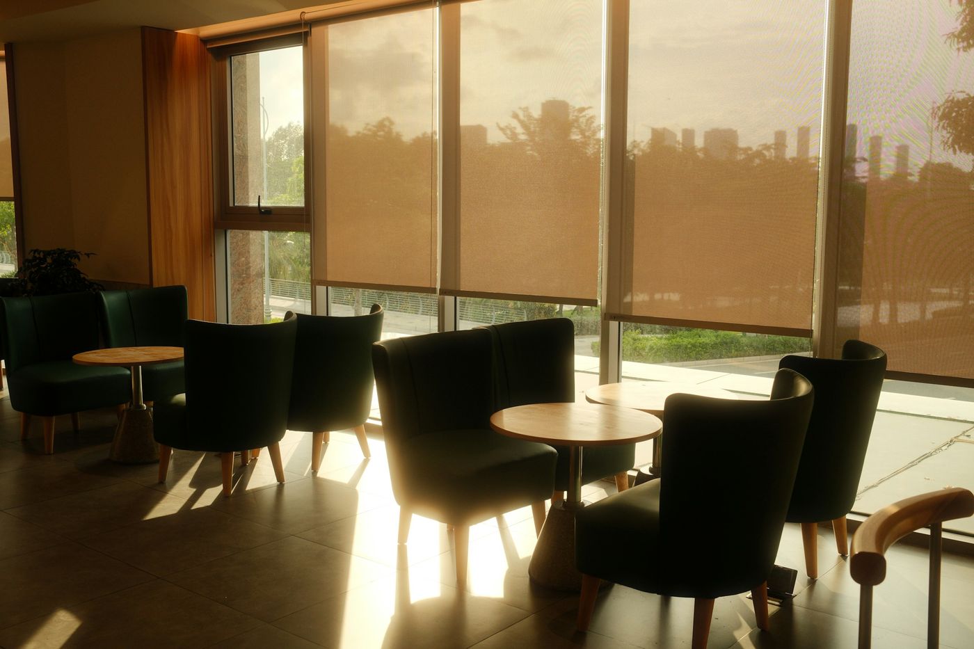 Lounge with roller shades lowered against warm afternoon sun streaming through tall windows
