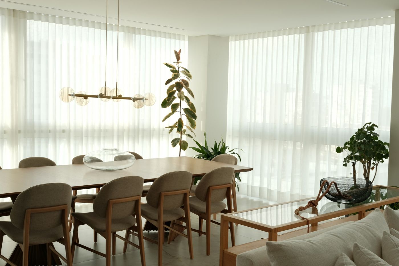 Modern dining room with sheer window coverings softening daylight from floor-to-ceiling windows