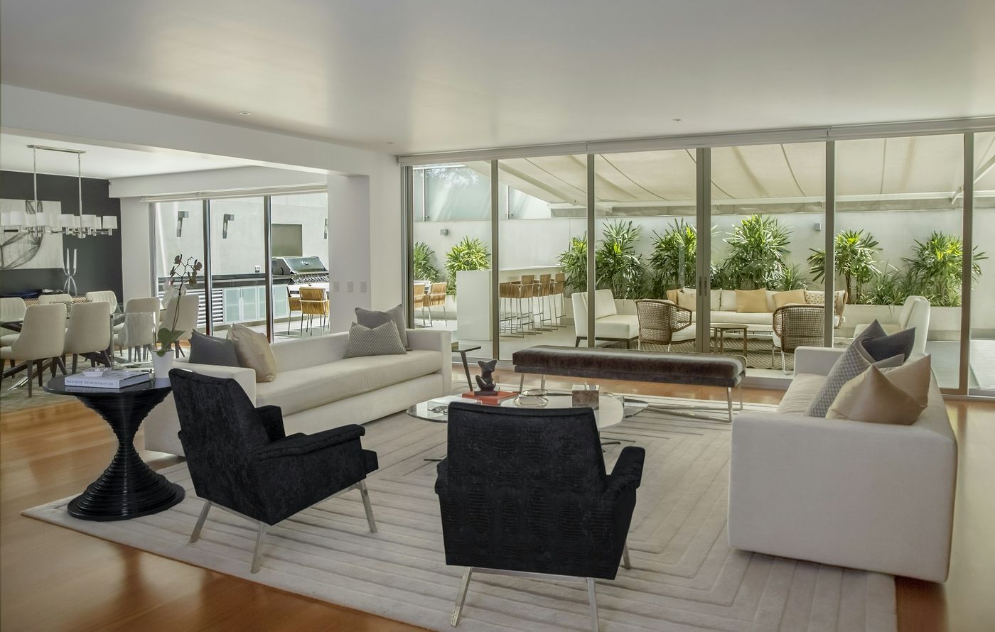 Spacious open living room with armchairs, sofas and floor-to-ceiling glass doors to a garden