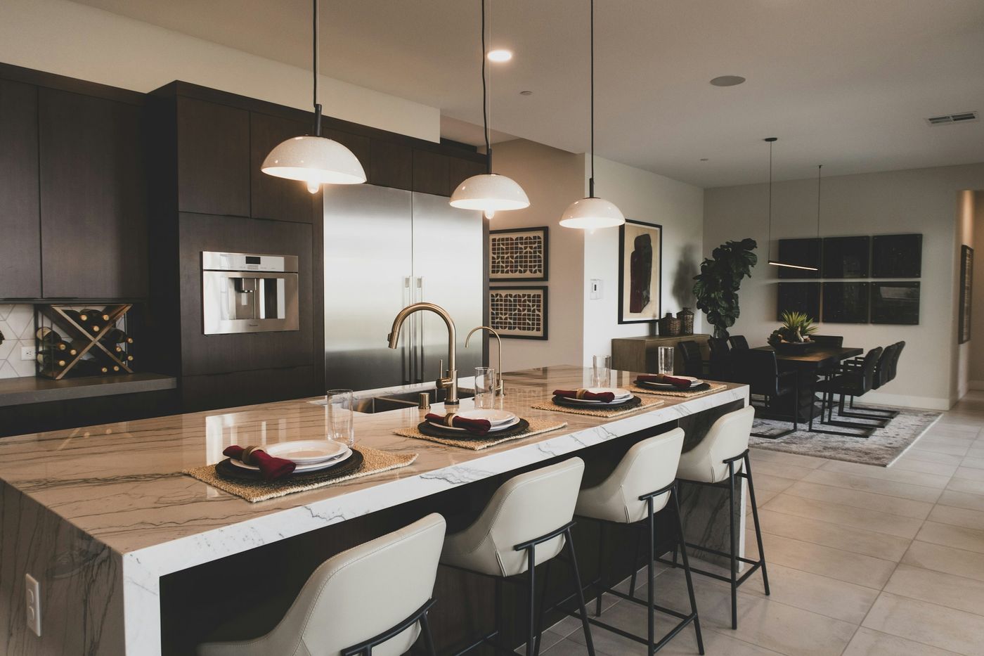 Kitchen island with three pendant lights and recessed lighting over a marble countertop