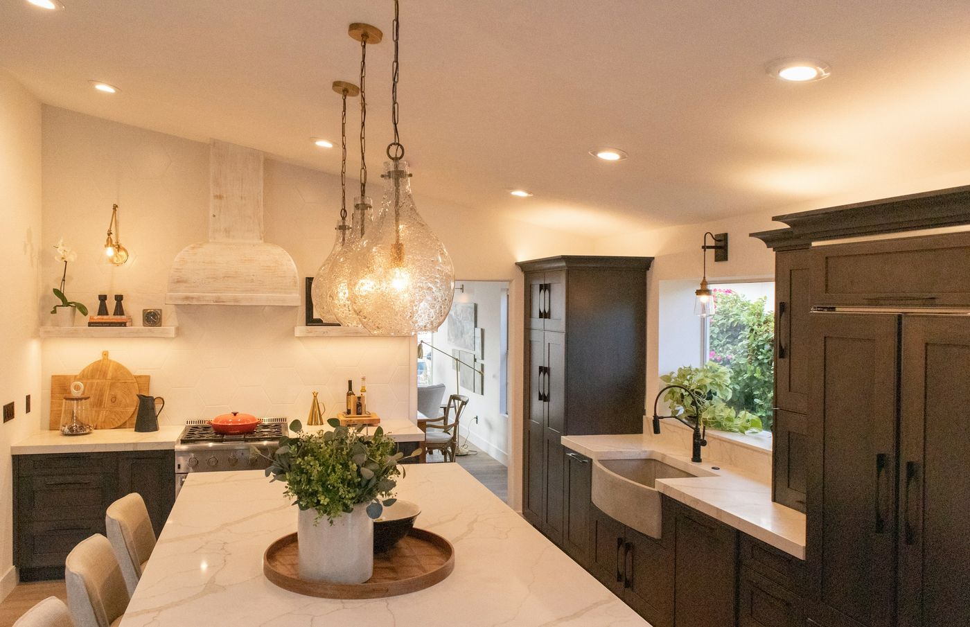 Kitchen in warm evening light with glass pendants over the island and recessed ceiling lights