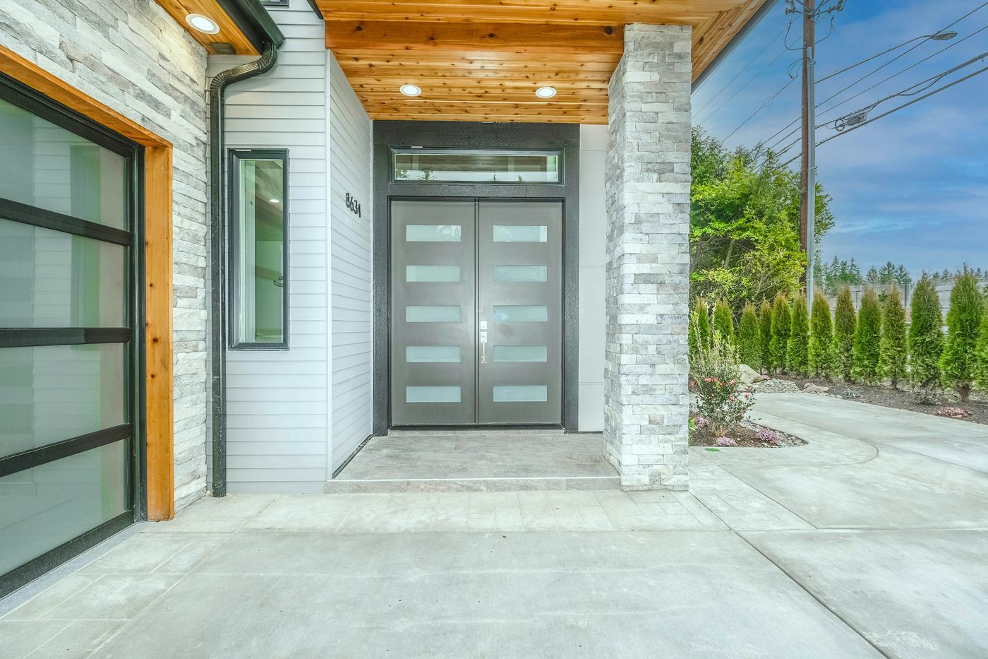 Modern double front door at a covered entry with stone and wood accents