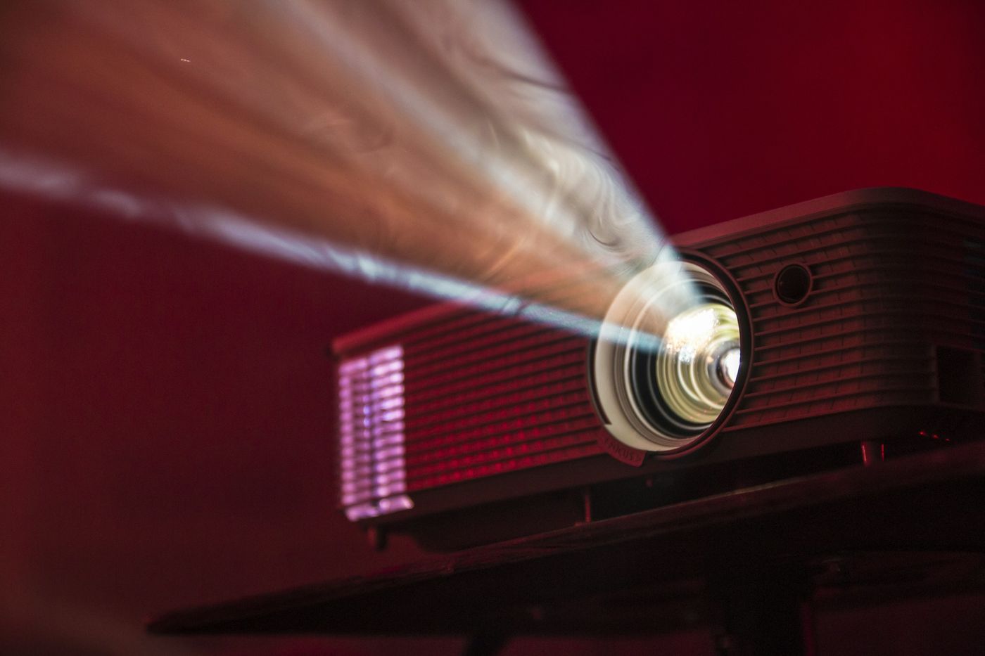 Projector beam shining from a lens in a dark room
