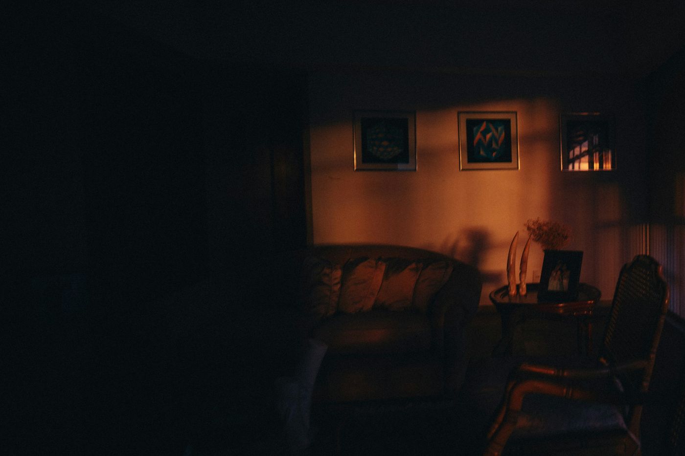 Dimly lit sitting room with soft lamp light and warm picture lights over framed art