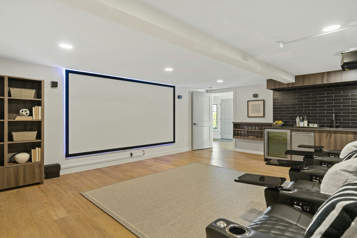 Bright media room with a large projection screen, recessed ceiling lights and theater recliners