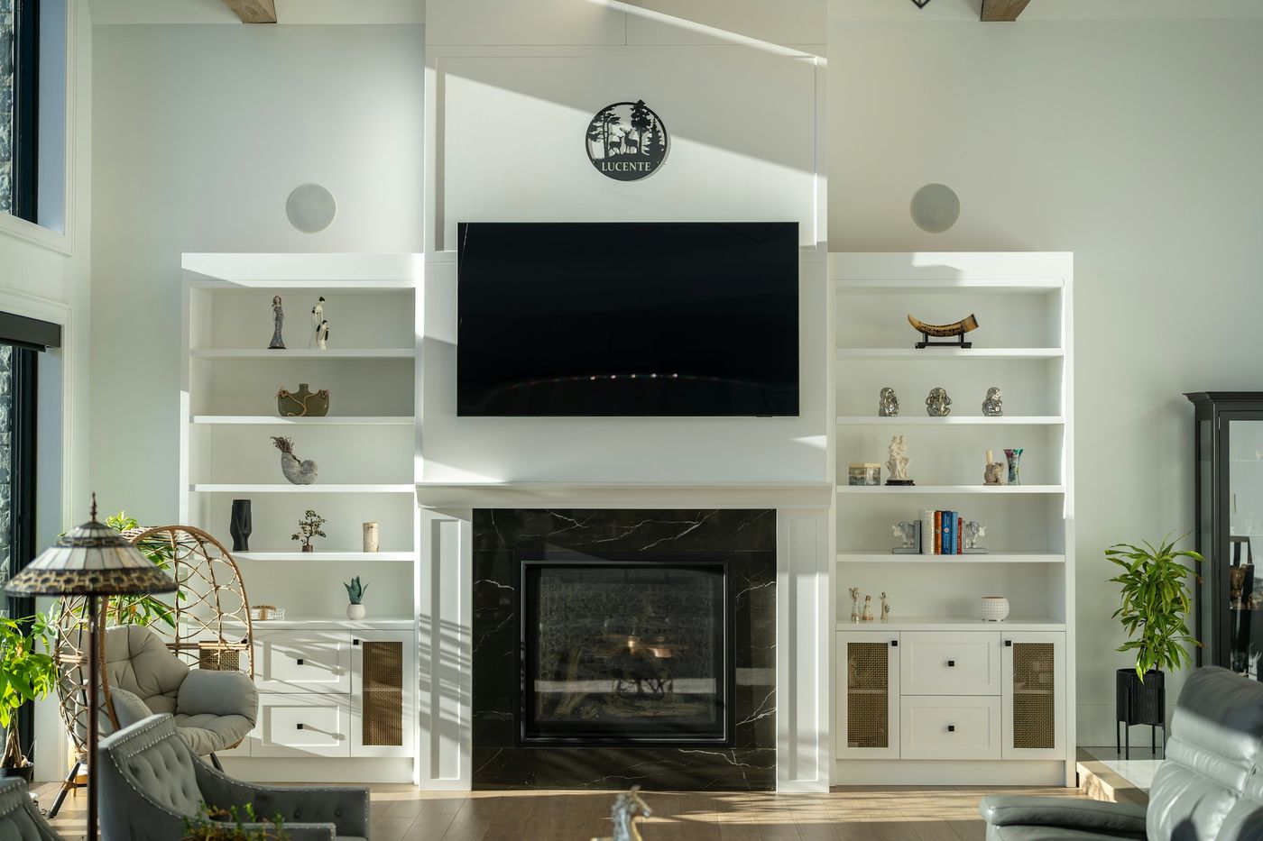 Living room with a TV above a fireplace, framed by built-in shelves, with speakers set into the ceiling
