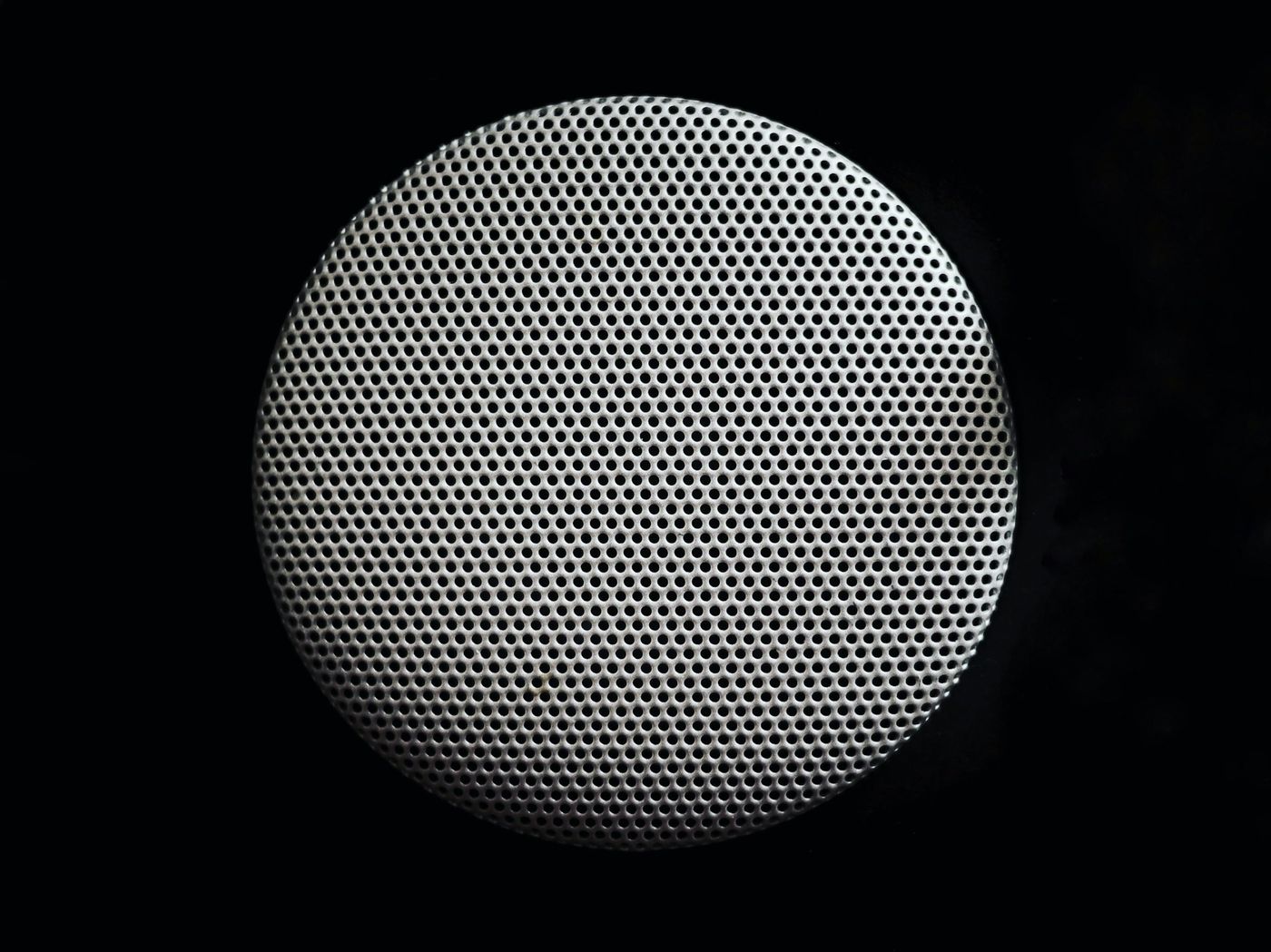 Close-up of a round perforated speaker grille