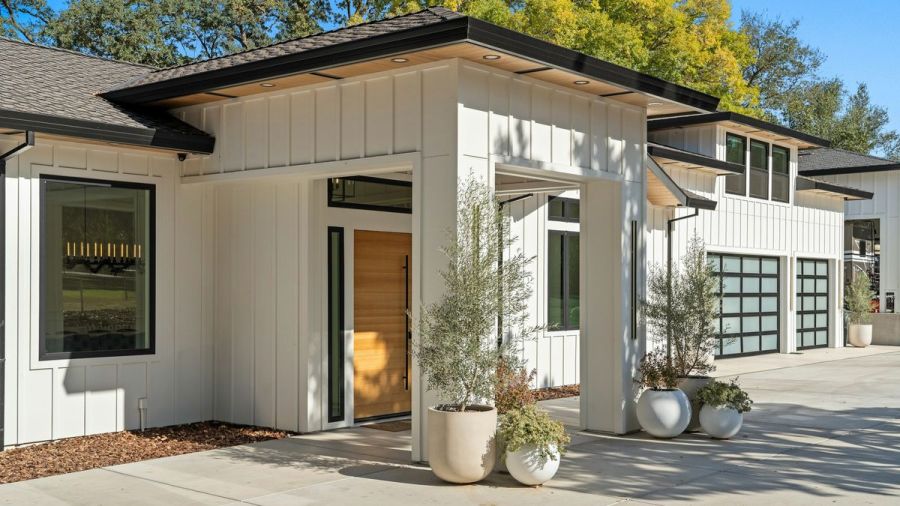 Modern white home with a wood front door and glass garage doors