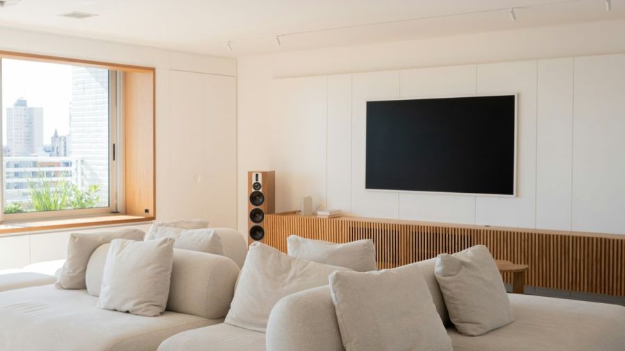 Bright living room with a large sectional sofa, wall-mounted TV and a floor-standing speaker