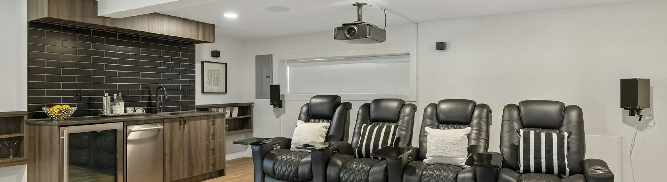 Media room with four leather theater recliners, a ceiling-mounted projector and a wet bar