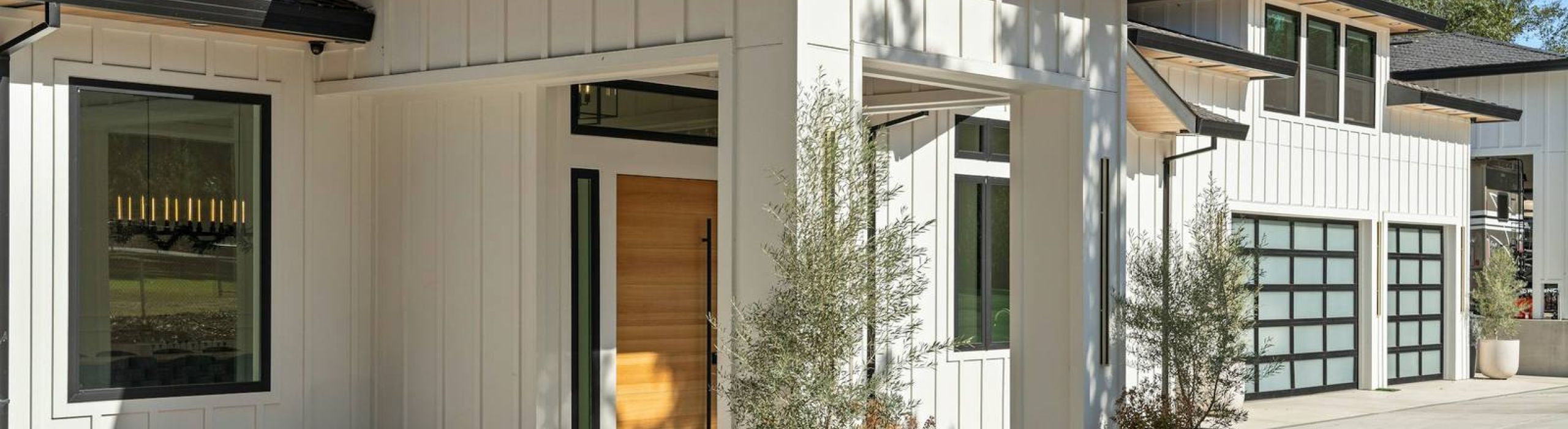 Modern white home with a wood front door and glass garage doors