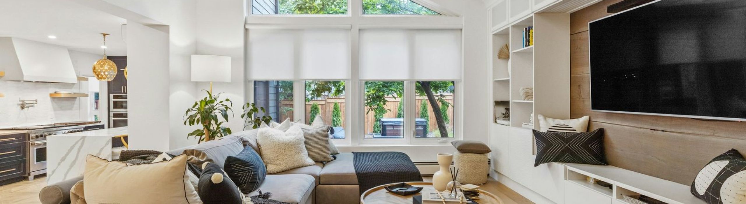 Bright family room with a sectional sofa, wall-mounted TV and shades on the upper windows